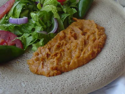 Shiro chickpea stew on injera with a fresh salad