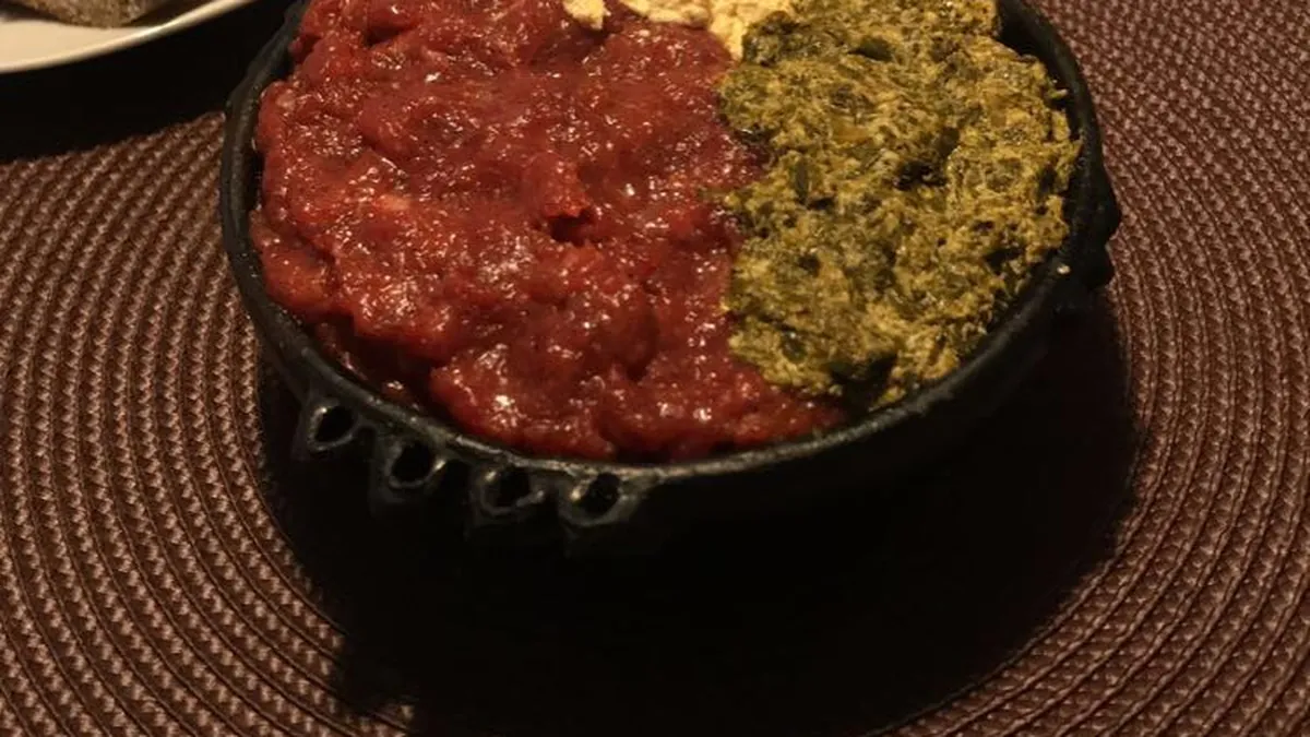 Special Kitfo with ayib and gomen in a black clay bowl