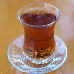 A glass of hot black tea on a saucer